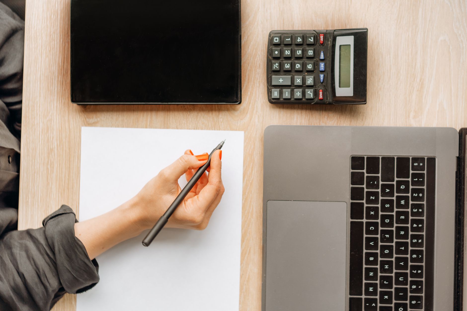 An agent working through numbers on a laptop and notepad