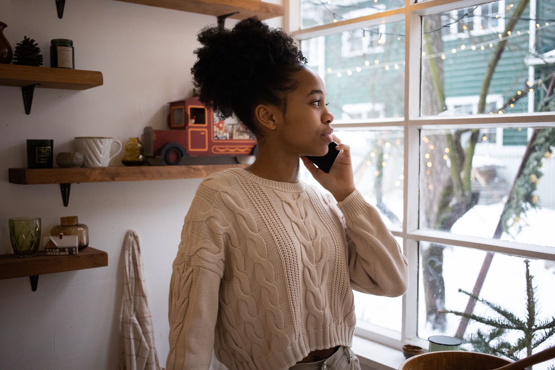 An agent having a relaxed phone conversation by a window with a mug